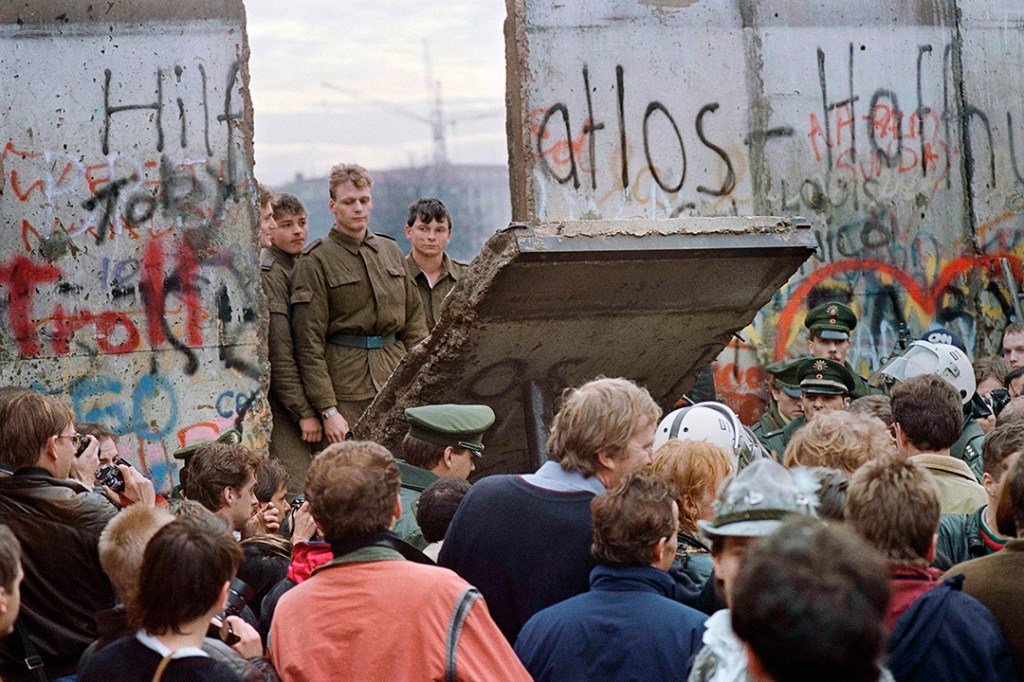 West Berliners crowd in front of the Berlin Wall in November 1989 as they watch East German guards demolish a section of the barrier to open a crossing point between East and West Berlin. 
