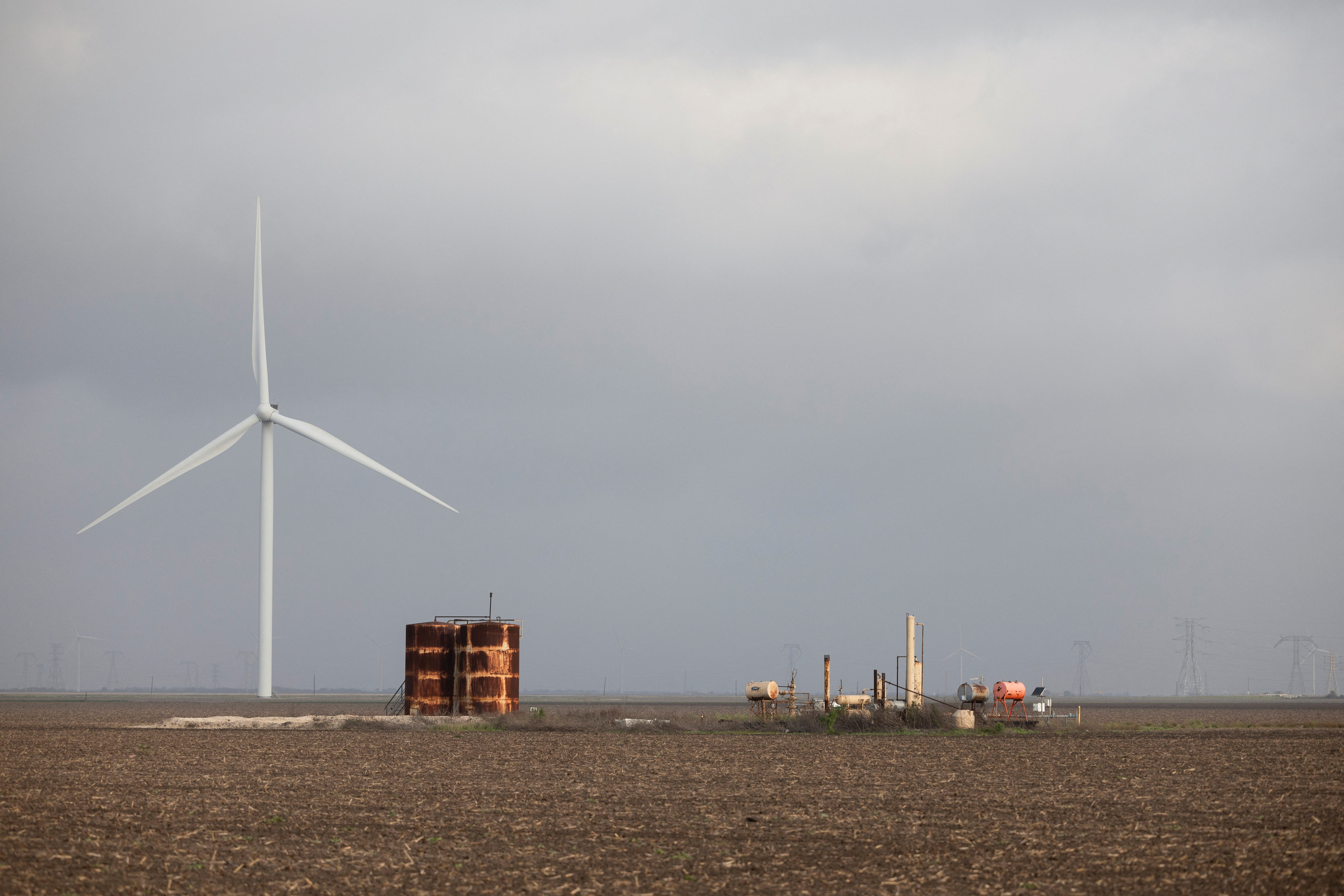 A wind turbine spins next to rusted metal structures in Gregory, Texas, U.S.