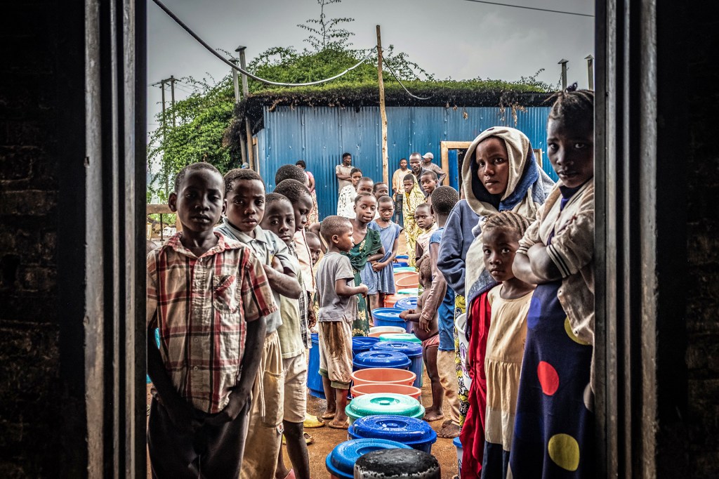 Refugees from eastern Democratic Republic of the Congo, newly arrived after renewed fighting broke out, line up with buckets at a food distribution point at Nyarushishi Transit Camp in Rusizi district on December 11, 2025.