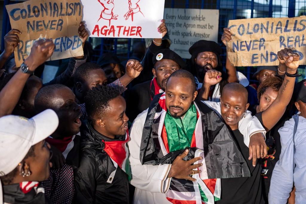 Kenyan journalist and human rights activist Boniface Mwangi (C) embraces his wife Njeri Mwangi as he reacts to a welcome by supporters and activists following his release from detention by Tanzanian authorities at the Wilson Airport in Nairobi on May 22, 2025.