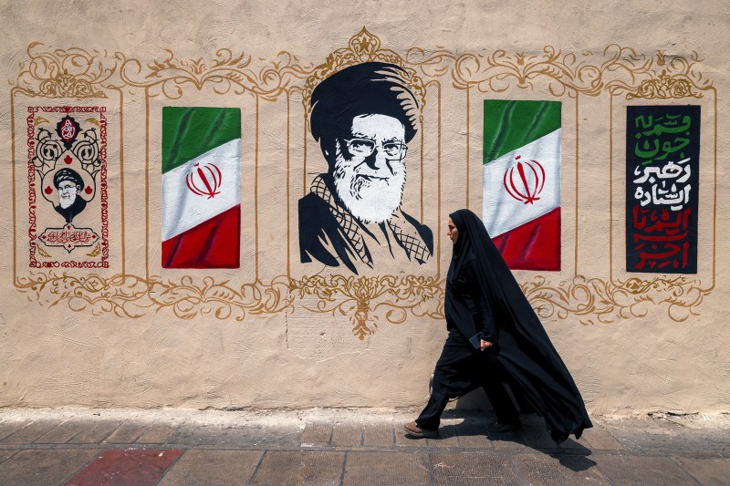 A woman walks past a mural depicting Iran's late supreme leader Ali Khamenei at Valiasr Square in central Tehran on August 8, 2026.