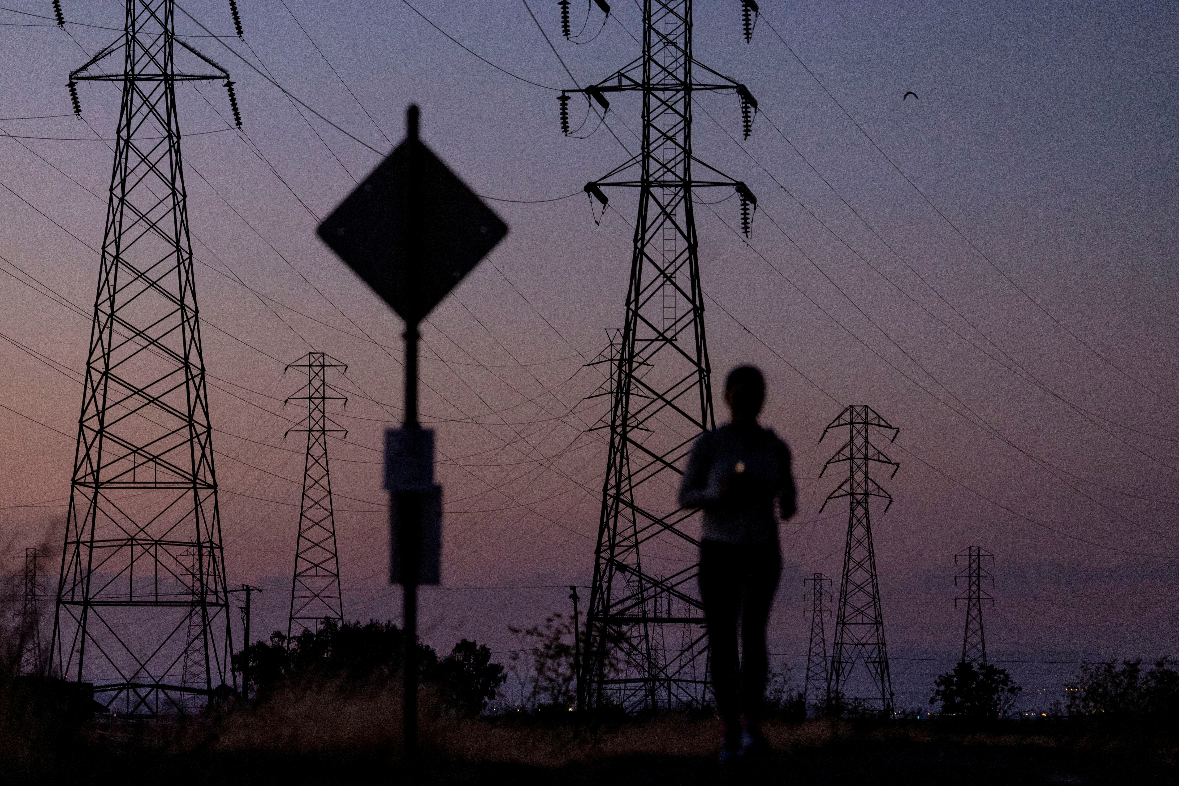 A woman jogs by power lines in California in August 2022.