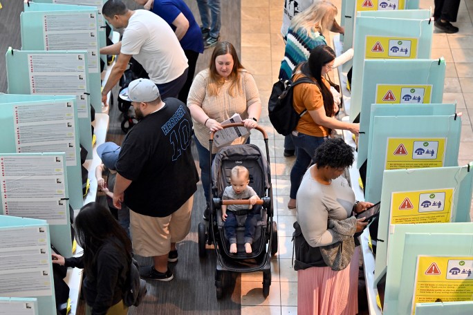 A woman with a child makes her way through voters inside the Galleria at Sunset mall on November 05, 2024 in Las Vegas, Nevada.